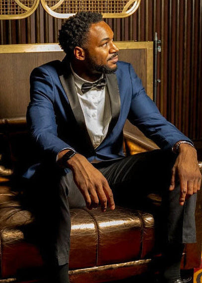 Man in a blue suit sitting on a leather couch in a stylish room.