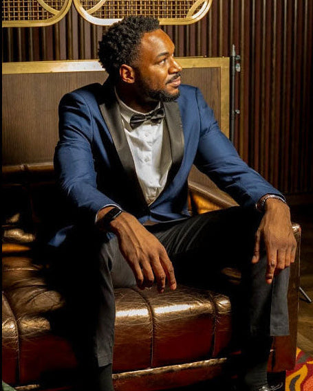Man in a blue suit sitting on a leather couch in a stylish room.